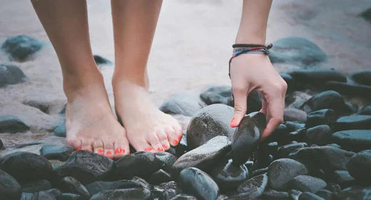 Pair of feet of a person standing on a pebbled beach