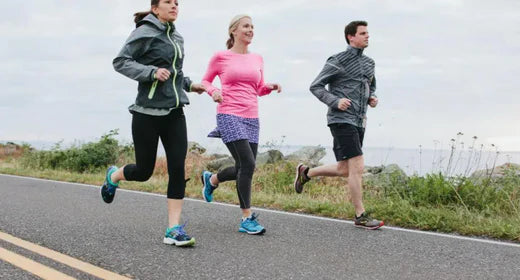 Three people running on a paved road