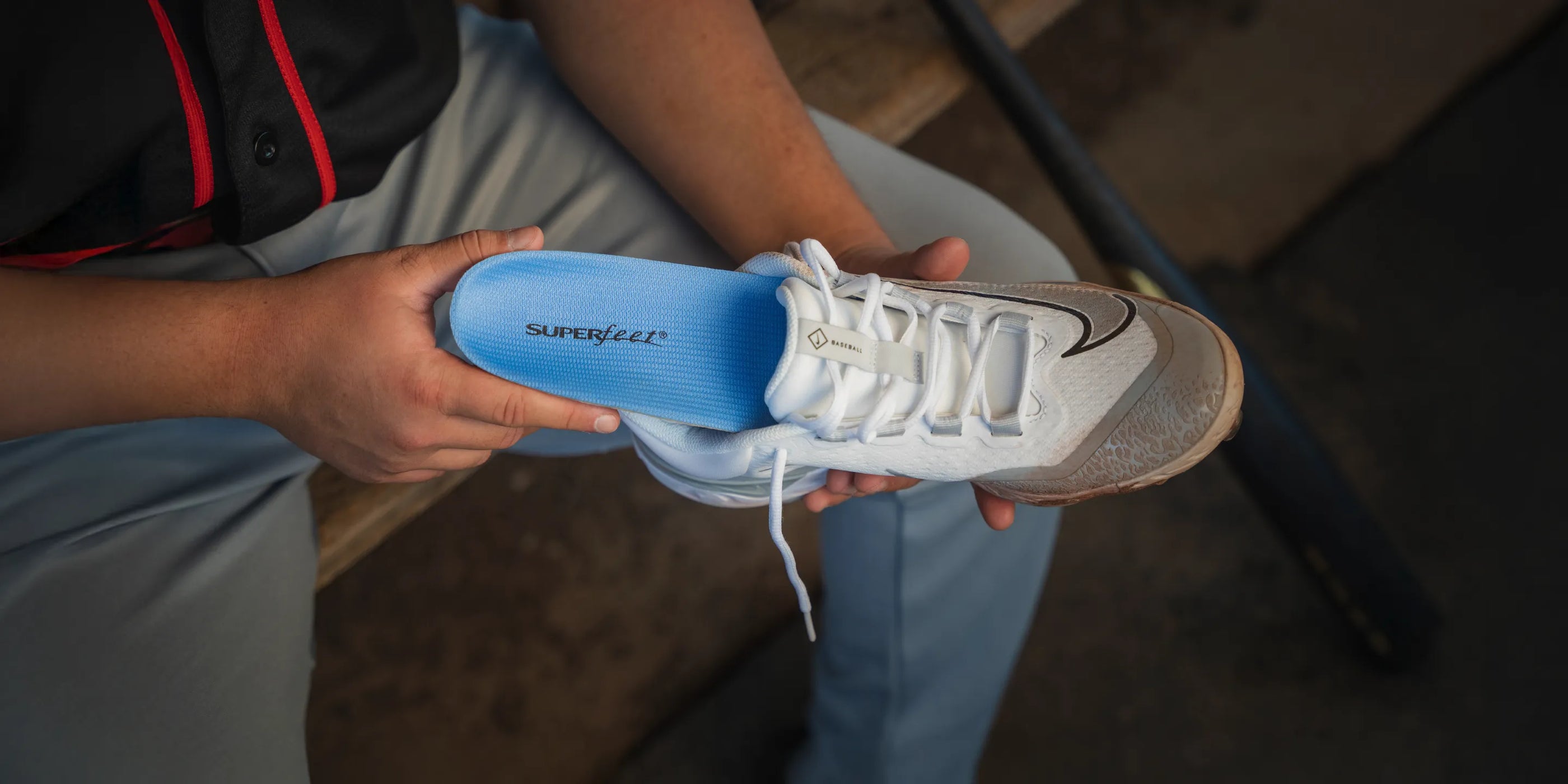 Baseball player holding cleated shoe and inserting a Superfeet insole into it.