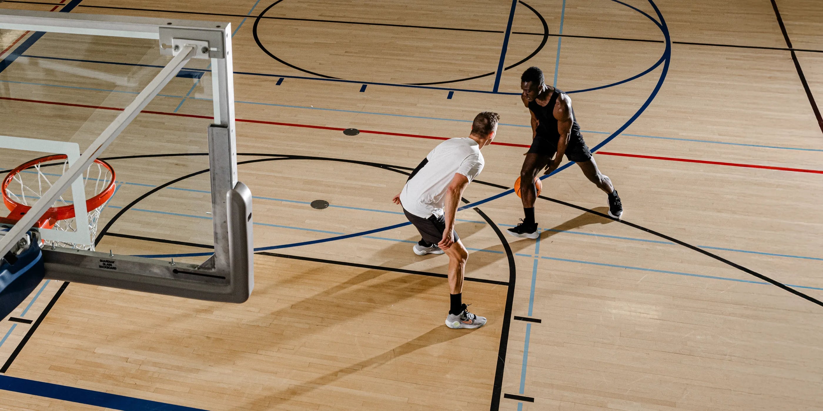 Men on gym basketball court, playing basketball.