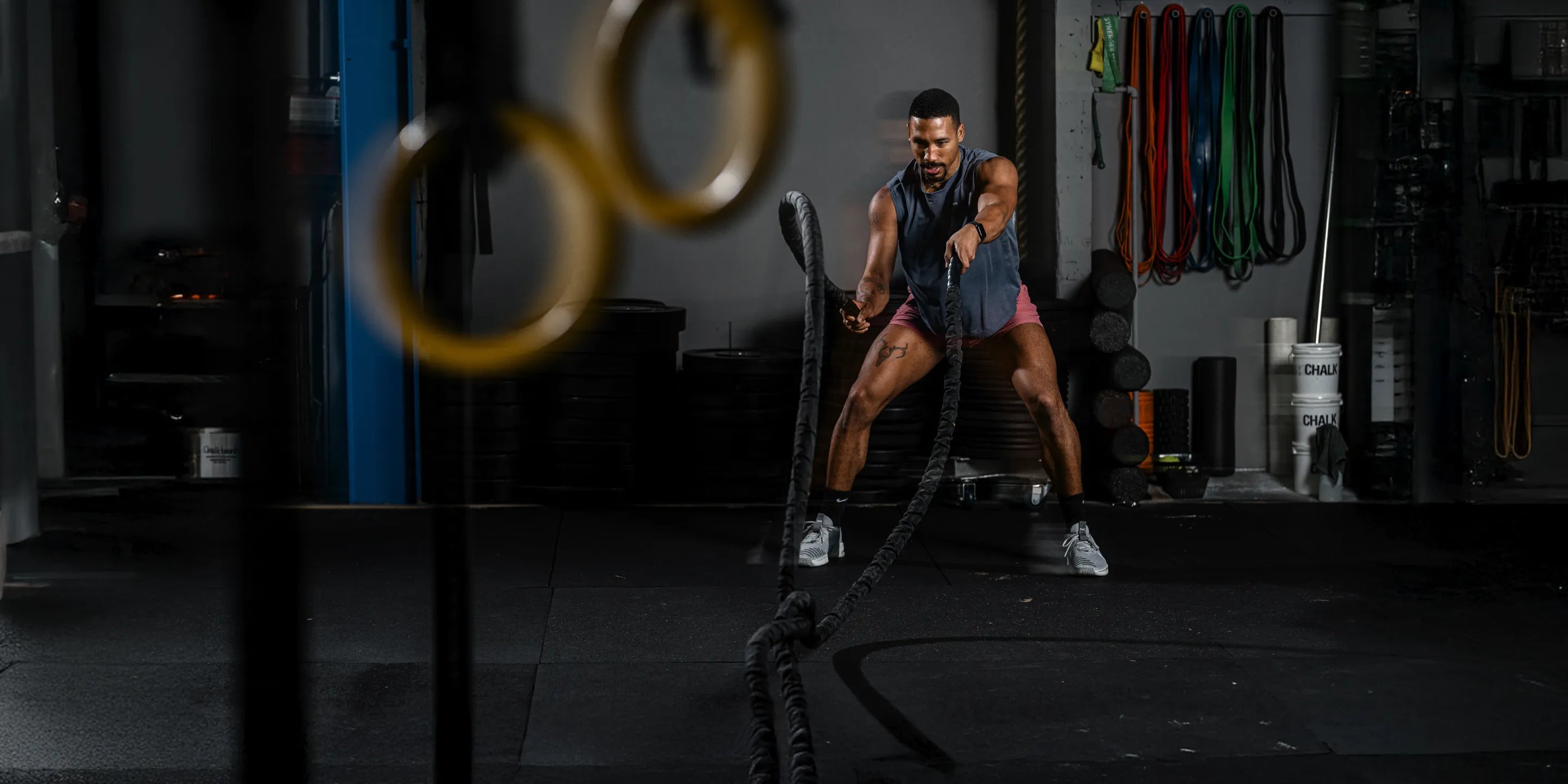 Man in cross fit gym using heavy ropes to perform the battle rope exercise.