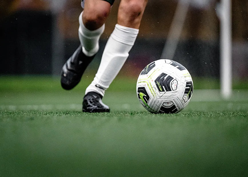 Man playing soccer and approaching the ball to kick it while wearing Superfeet insoles.