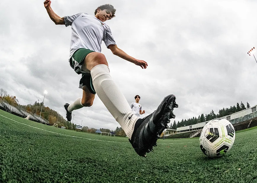 Boy playing soccer approaching the ball to kick it while wearing Superfeet insoles.