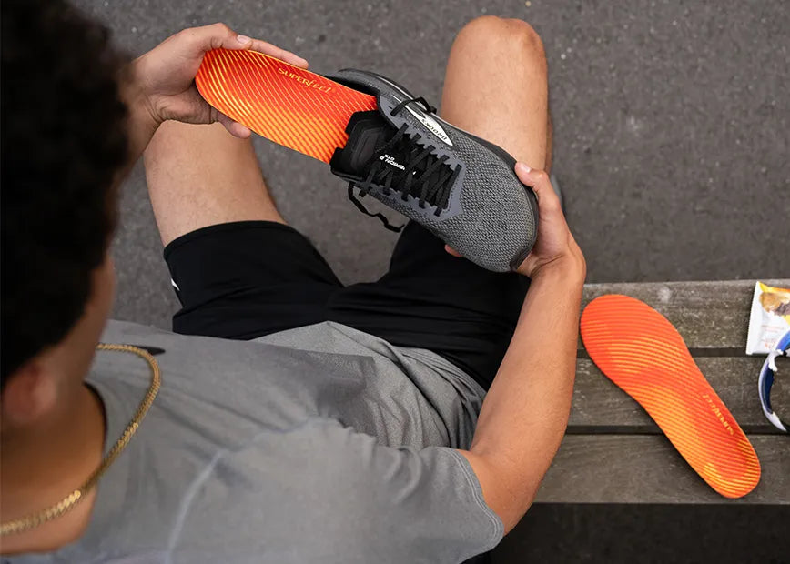 Runner putting a run pain relief insole in a running shoe