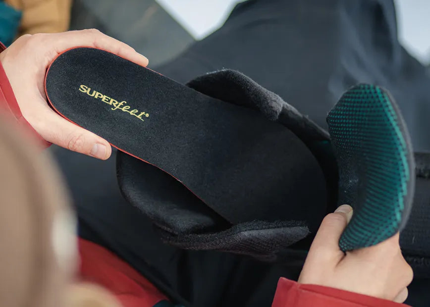 Person inserting a Superfeet Winter Thin Support Insole into a snowboard boot.