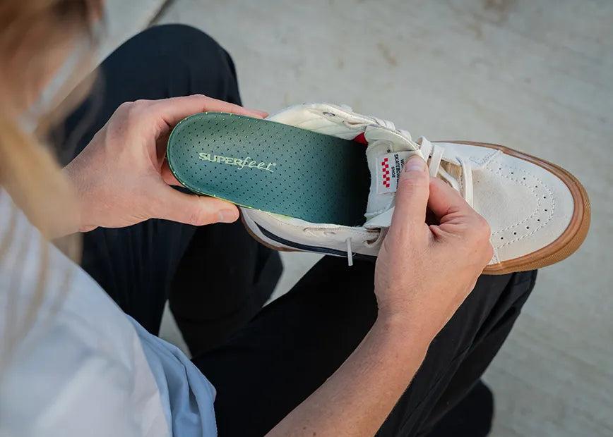 Man inserting Superfeet Casual Pain Relief insole into a walking shoe.