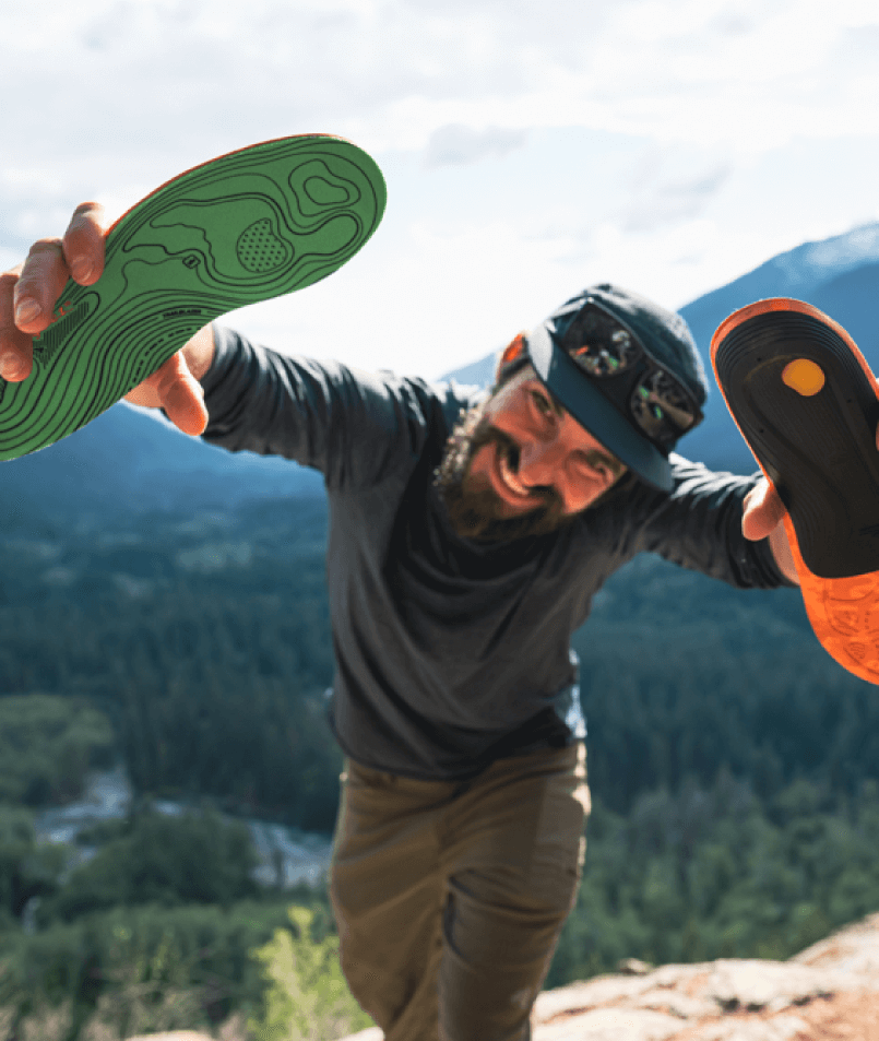 Hiker in wilderness showing Superfeet insoles to camera